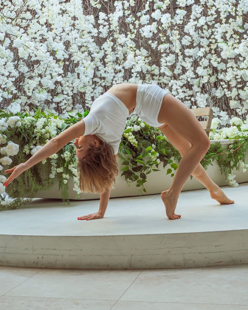 Graceful woman practicing calm yoga movements in soft violet light